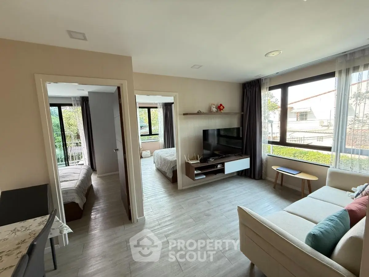 Spacious living room with modern decor and natural light, connecting to two cozy bedrooms.
