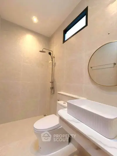 Modern bathroom with sleek fixtures and elegant design, featuring a round mirror and spacious shower area.
