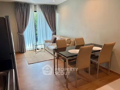 Modern living room with dining area, featuring elegant furniture and large window with curtains.