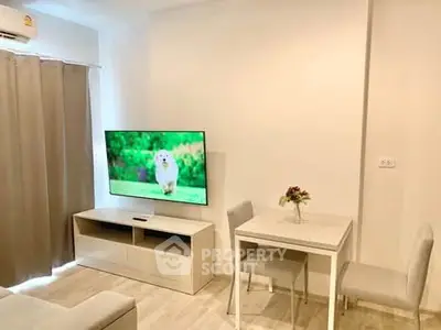 Modern living room with wall-mounted TV and cozy dining area in stylish apartment.