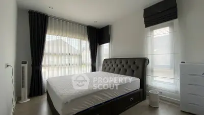 Modern bedroom with large windows and elegant curtains, featuring a stylish bed and sleek flooring.