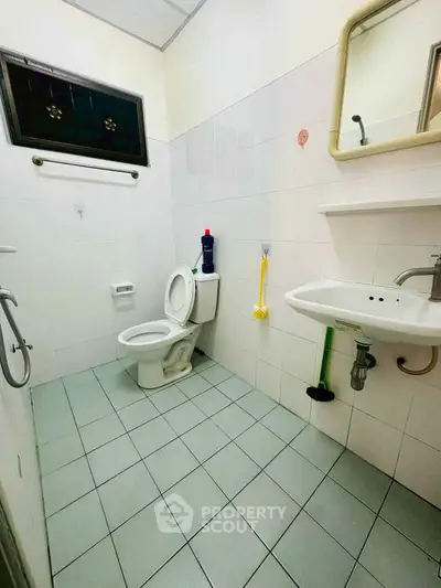 Spacious bathroom with modern fixtures and tiled flooring, featuring a toilet and sink.