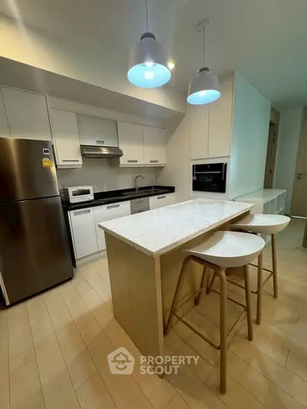 Modern kitchen with island, stainless steel appliances, and stylish lighting in a contemporary apartment.