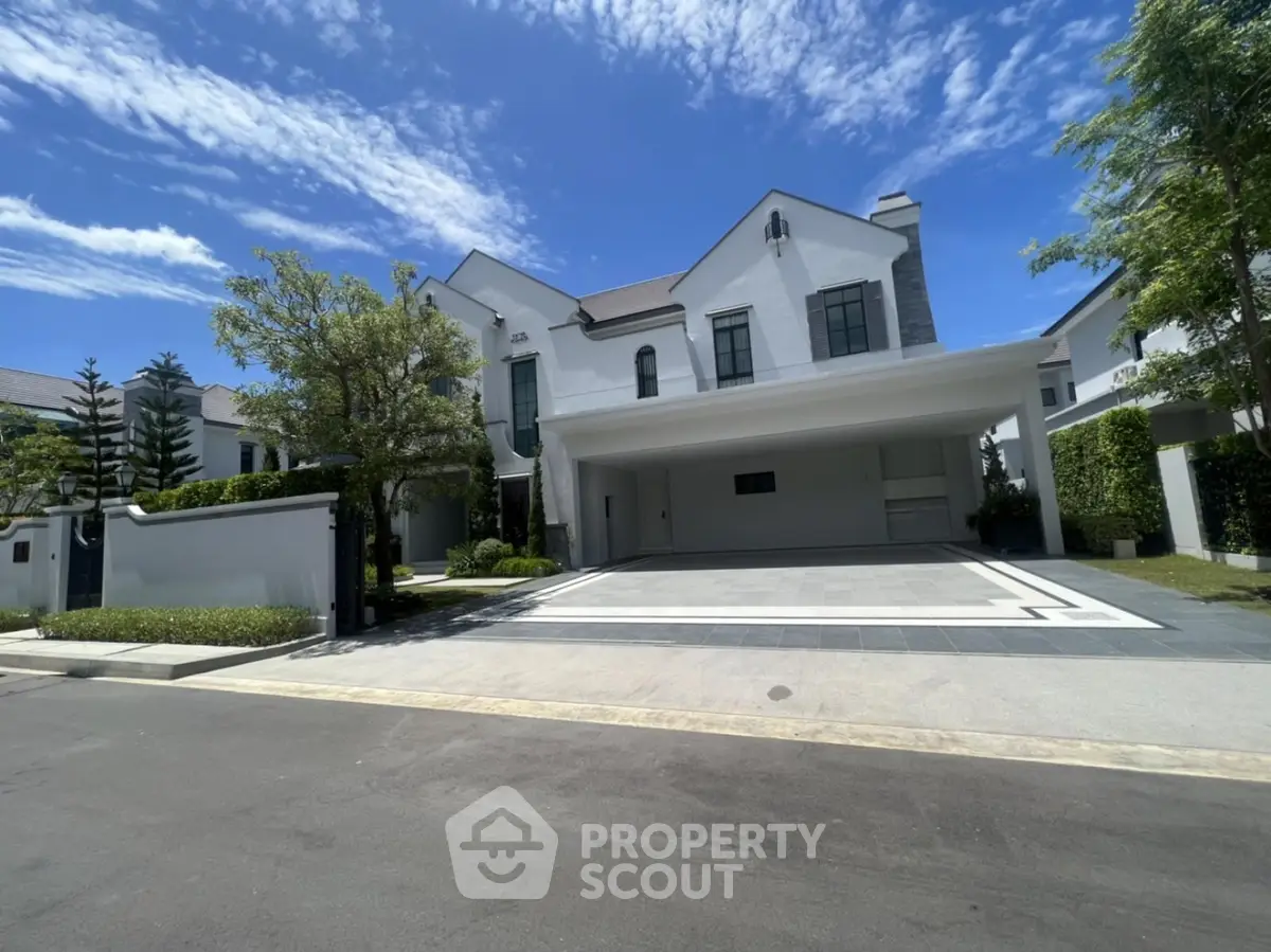 Luxurious modern villa with spacious driveway and elegant facade under clear blue sky.