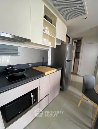 Modern kitchen with sleek cabinetry, built-in appliances, and stylish dining area in a contemporary apartment.