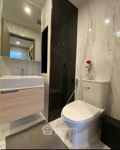 Modern bathroom with sleek fixtures and elegant marble walls, featuring a stylish vanity and contemporary toilet.