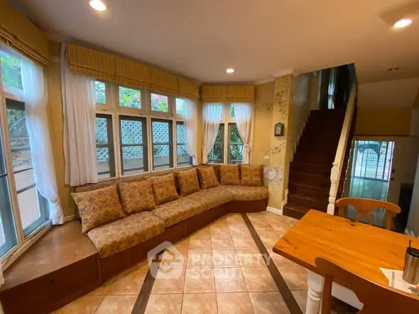 Charming living room with large windows and cozy built-in seating, perfect for relaxation and entertaining.