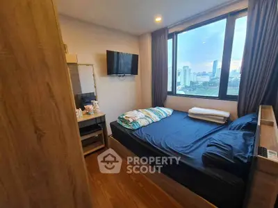 Cozy bedroom with city view, featuring a mounted TV and wooden furnishings, perfect for urban living.