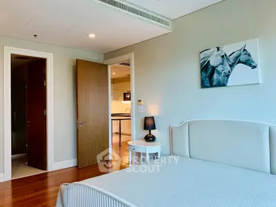 Modern bedroom with elegant decor and open door leading to a stylish kitchen.