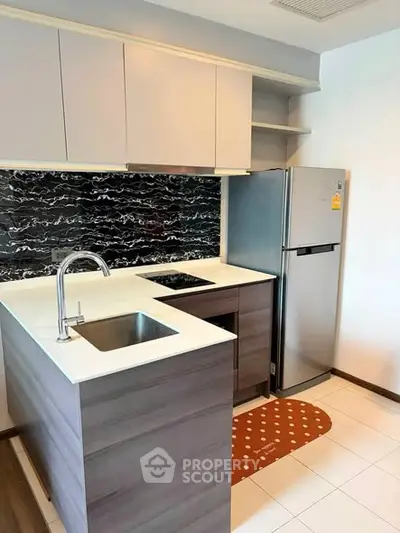 Modern kitchen with sleek cabinetry and stainless steel fridge in a stylish apartment.