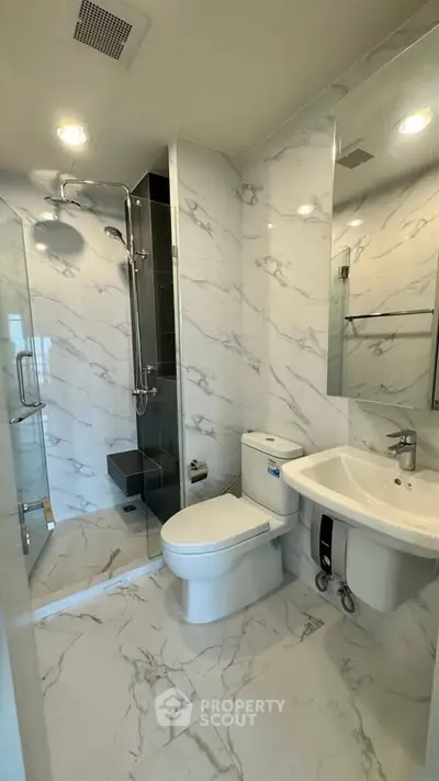 Luxurious modern bathroom with marble tiles and glass shower enclosure