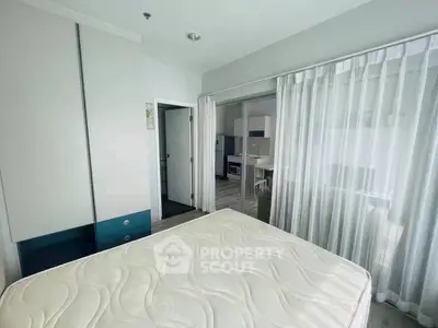 Modern bedroom with open layout to kitchen, featuring sleek design and natural light.