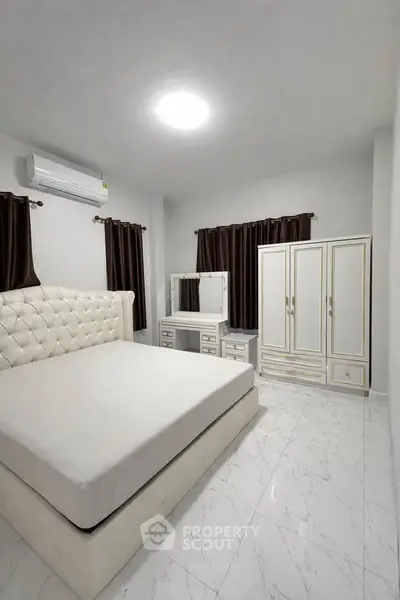 Elegant bedroom with white furniture and air conditioning, featuring a plush bed and stylish wardrobe.