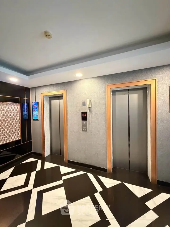 Modern building elevator lobby with stylish geometric flooring and sleek elevator doors.
