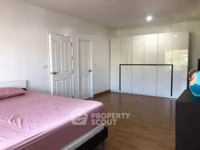 Spacious bedroom with modern wardrobe and wooden flooring, perfect for comfort and style.