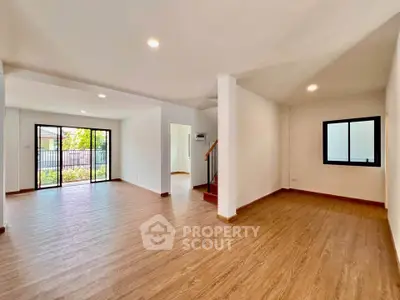 Spacious open-plan living room with wooden flooring and large windows