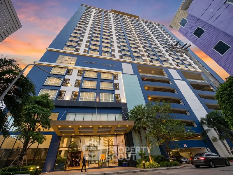 Stunning modern high-rise building with sunset backdrop and lush greenery.