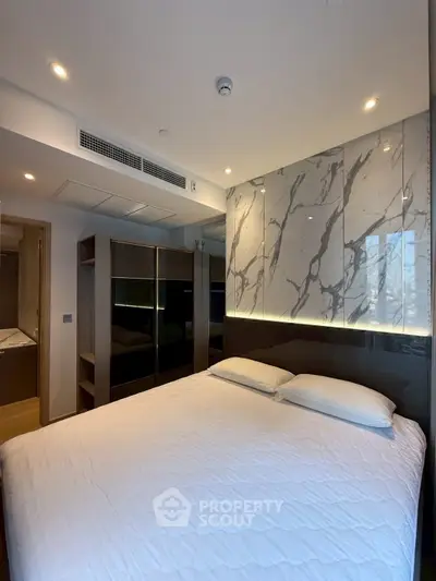 Modern bedroom with stylish marble accent wall and sleek wardrobe design.