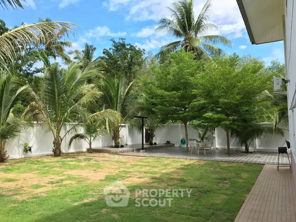 Spacious tropical garden with lush greenery and palm trees, perfect for outdoor relaxation and entertainment.