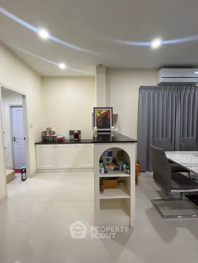 Modern open-plan kitchen and dining area with sleek furniture and bright lighting.