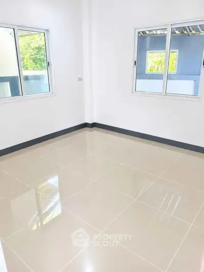 Spacious empty room with glossy tiled floor and large windows, perfect for customization.