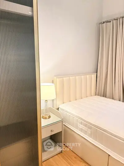 Cozy bedroom with elegant decor and soft lighting, featuring a plush bed and modern bedside table.