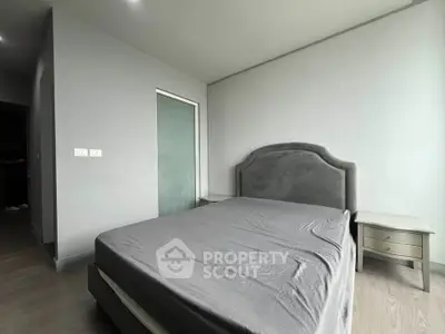 Modern bedroom with minimalist design and gray tones, featuring a plush headboard and sleek side tables.