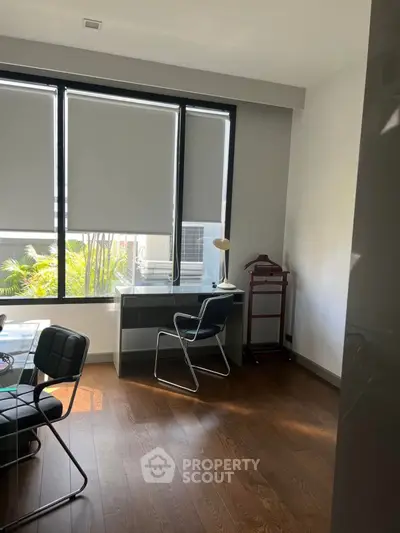 Bright study room with modern furniture and large windows overlooking greenery.