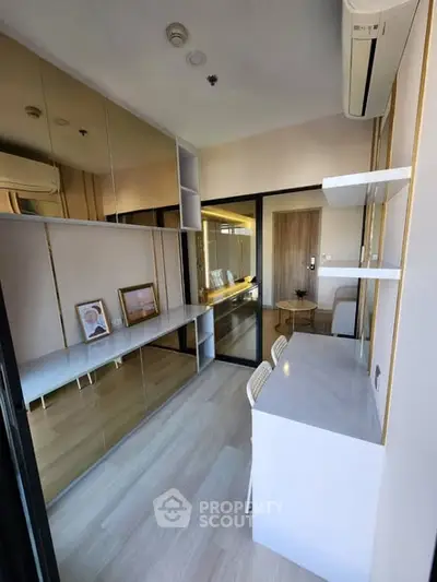 Modern study room with sleek design, mirrored wall, and built-in desk in a stylish apartment.