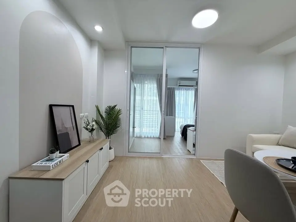 Modern living room with elegant decor and sliding glass doors leading to a bright bedroom.