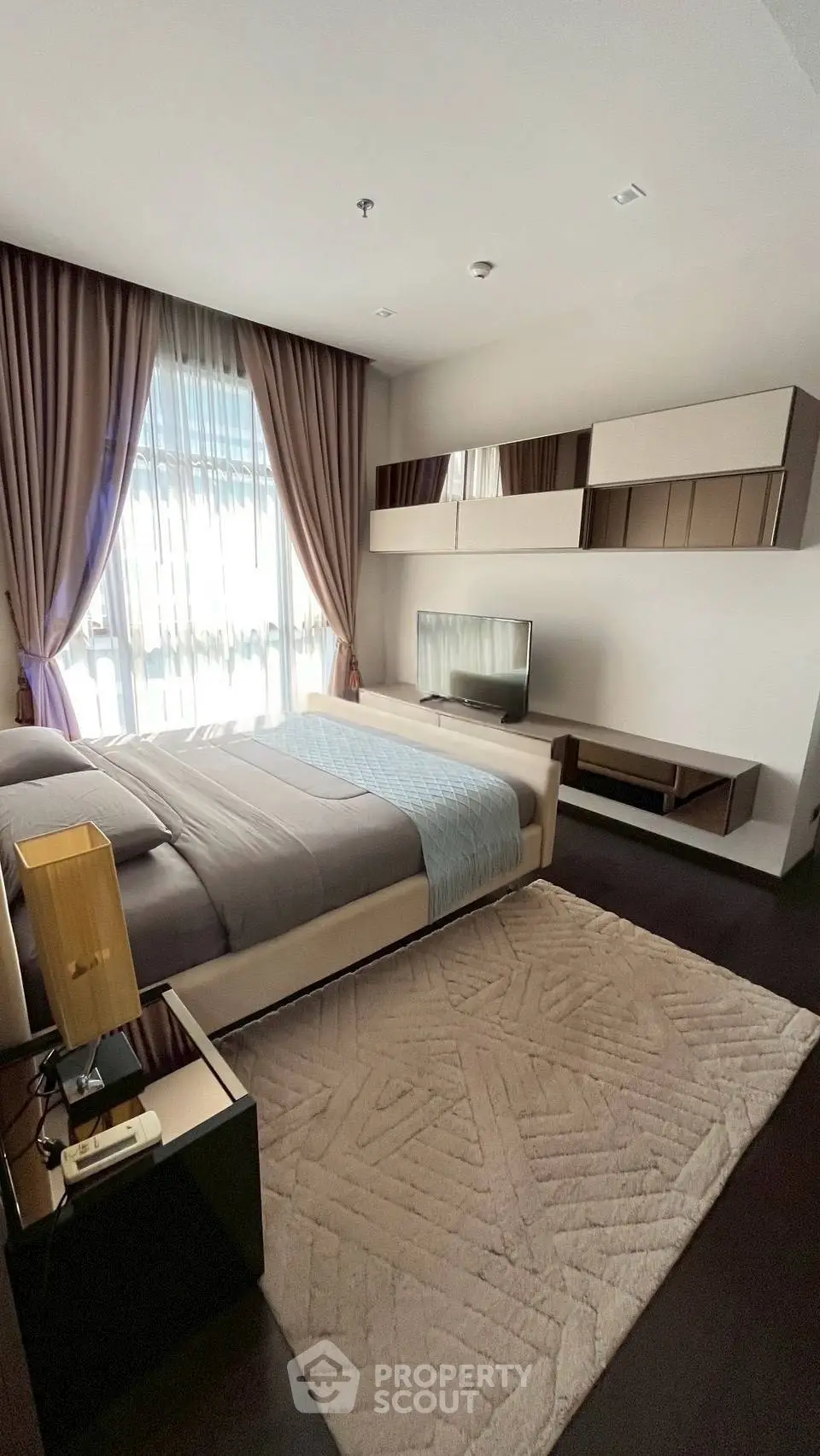 Luxurious bedroom with modern decor, large window, and stylish furniture in a high-end apartment.