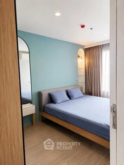 Modern bedroom with blue accent wall and stylish furnishings in a cozy apartment.