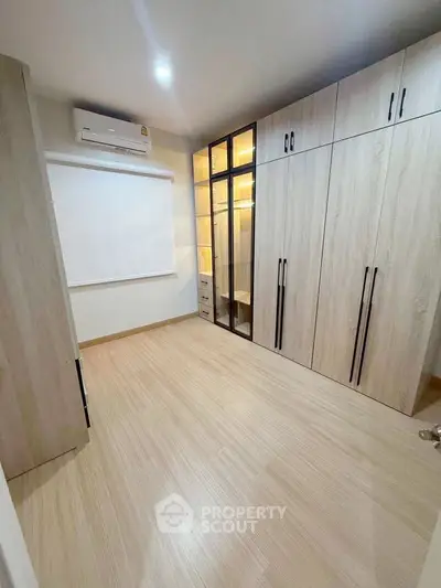 Spacious modern bedroom with built-in wardrobes and sleek wooden flooring.