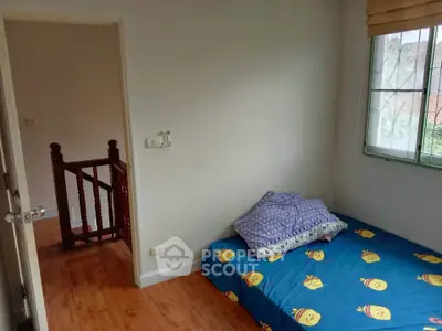 Cozy small bedroom with wooden flooring and cheerful bedding, perfect for a child's room.