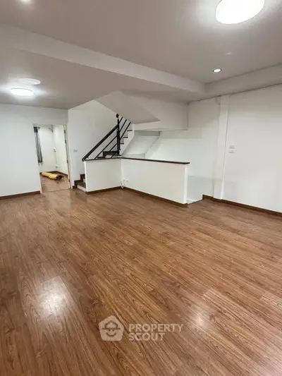 Spacious open-plan living area with wooden flooring and modern staircase.