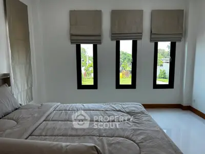 Spacious bedroom with large windows and garden view, featuring modern decor and natural light.