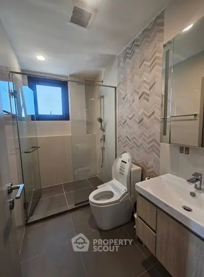 Modern bathroom with glass shower and sleek fixtures in contemporary apartment.