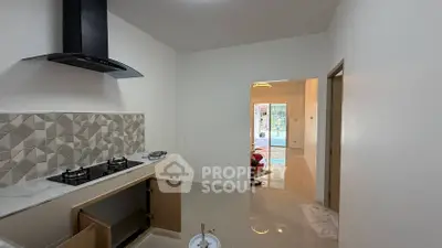 Modern kitchen with sleek gas stove and open layout leading to living area.