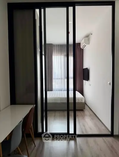 Modern bedroom with sliding glass doors and natural light, featuring a sleek design and comfortable ambiance.