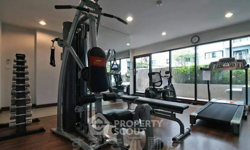 Modern gym with state-of-the-art equipment and large windows in a residential building.