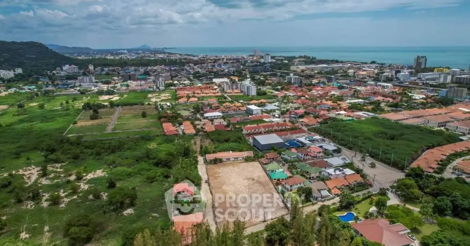 Stunning aerial view of coastal cityscape with lush greenery and ocean horizon, ideal for real estate development.