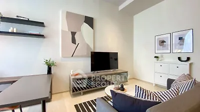 Modern living room with stylish decor, featuring a sleek TV stand, abstract art, and cozy seating area.