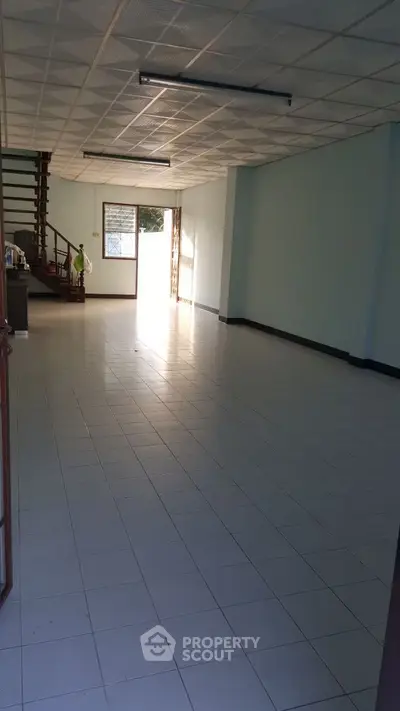 Spacious open-plan interior with tiled flooring and staircase, ideal for customization.