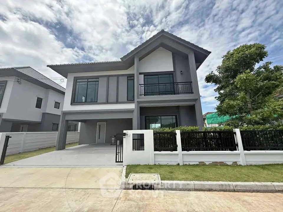 Modern two-story house with sleek design and spacious driveway under a clear sky.