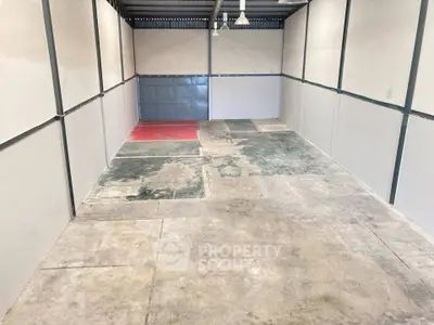 Spacious industrial storage unit with concrete flooring and high ceiling.