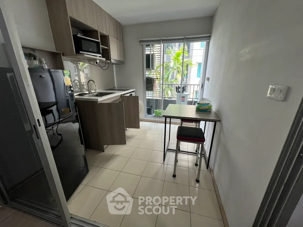 Modern kitchen with sleek cabinetry and compact dining area, featuring large windows for natural light.
