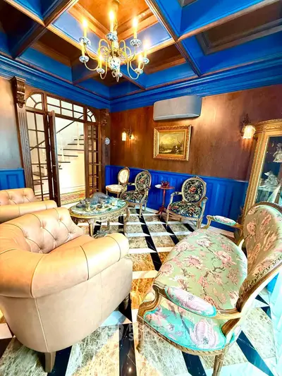 Luxurious living room with elegant furniture and chandelier, featuring classic design and marble flooring.
