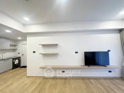 Modern living room with sleek TV setup and open kitchen layout