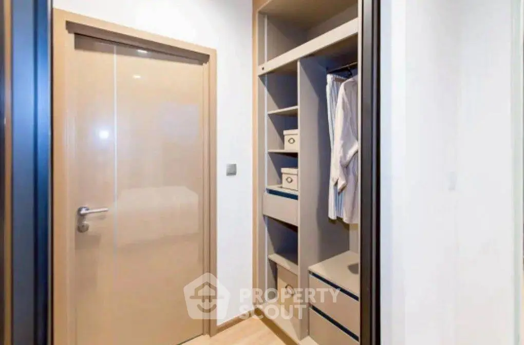 Modern storage space with built-in shelves and hanging area in a stylish apartment.