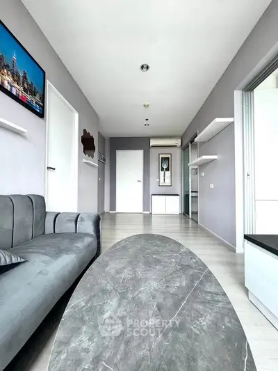 Modern living room with sleek gray sofa and marble coffee table, bright and spacious interior design.